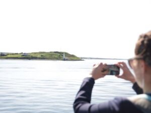 Une personne portant des lunettes de soleil prend une photo d'une île avec son téléphone portable.