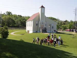 Photo aérienne d'un groupe de personnes marchant sur l'herbe devant une petite église.